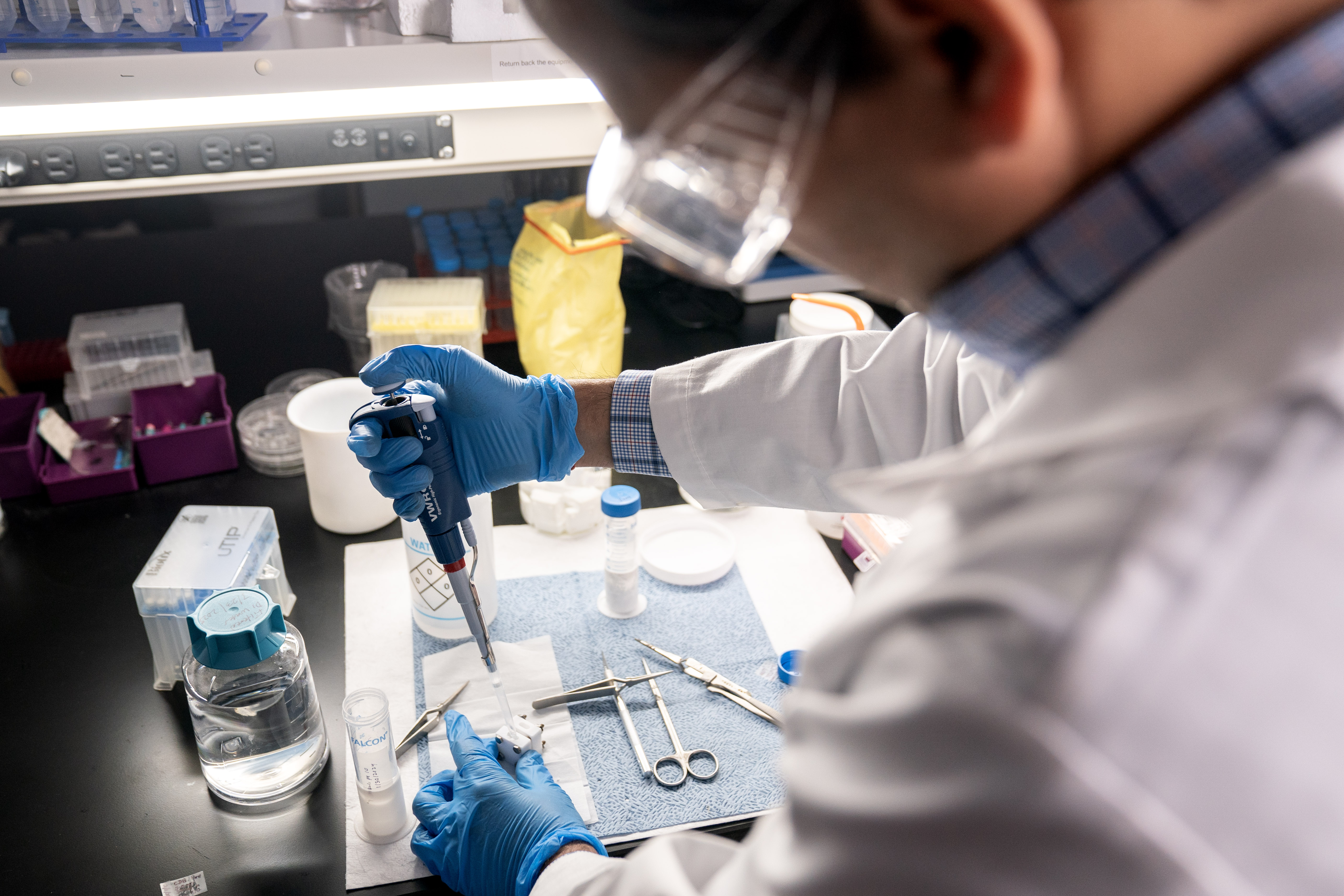 A faculty researcher works with a pipette in an SMU lab 