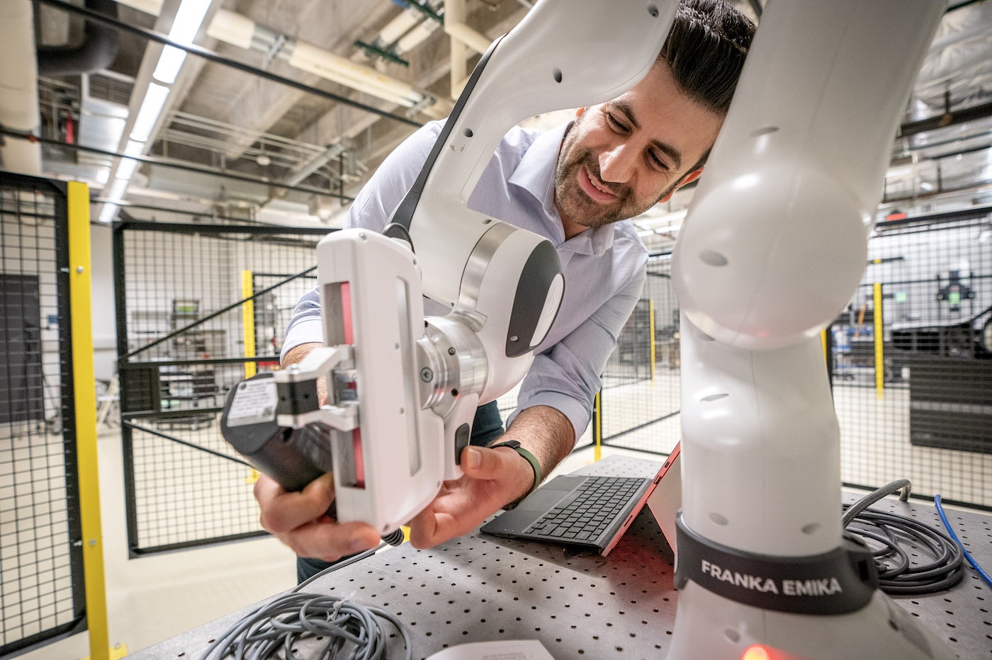 A researcher works with a robot arm in an engineering lab
