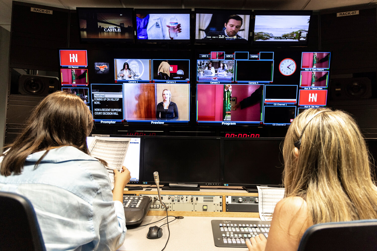 two female students looking at monitors in a broadcast room