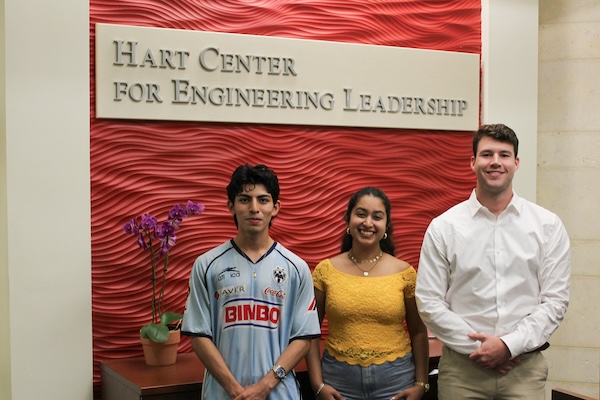 Three SMU Lyle students, two young men and one young woman, stand in front of the Har Center for Engineering Leadership Center, looking proud